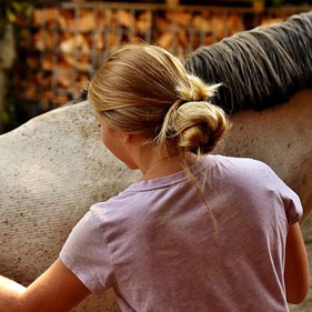 mujer de espaldas con caballo al fondo